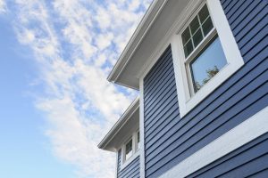 Blue siding on a two-story home with white trim. Sunny weather