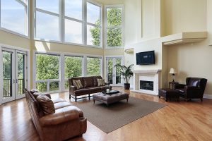 Living room with high ceilings and array of picture windows providing view of trees outside